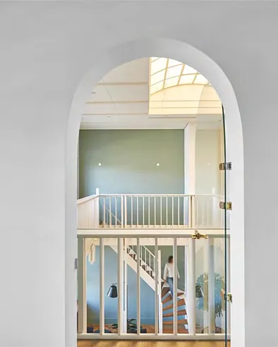 Arched opening framing a white stair and balustrade